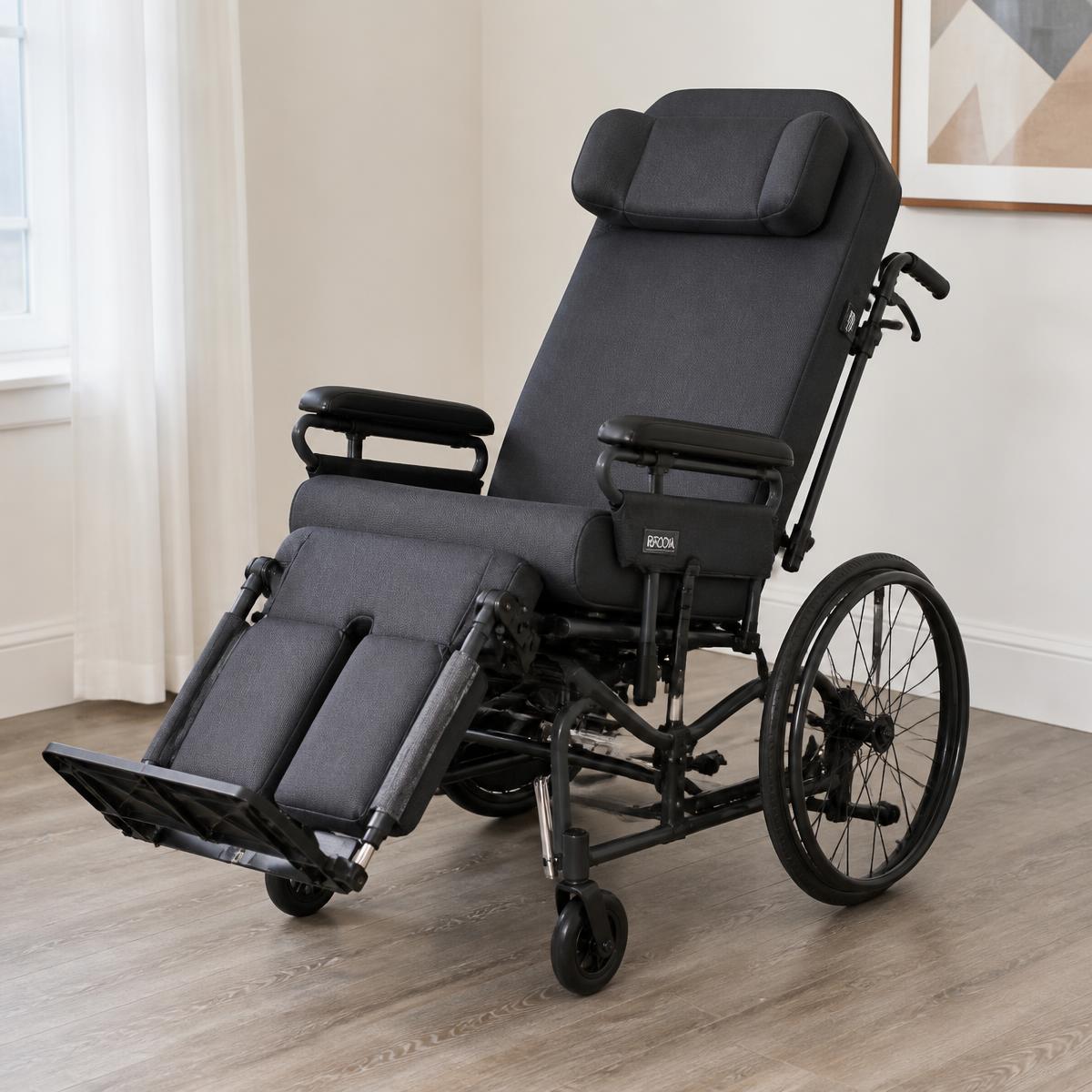 A dark gray reclining tilt-in-space mobility chair with padded headrest and elevated leg rest, similar to a Broda chair.